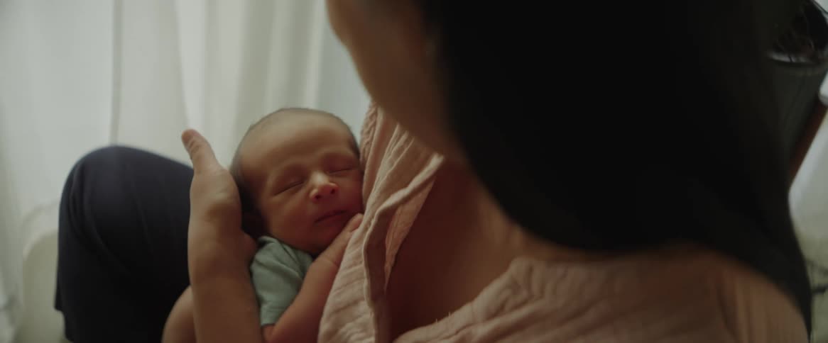 Mother holding her baby in her arms and stroking her head