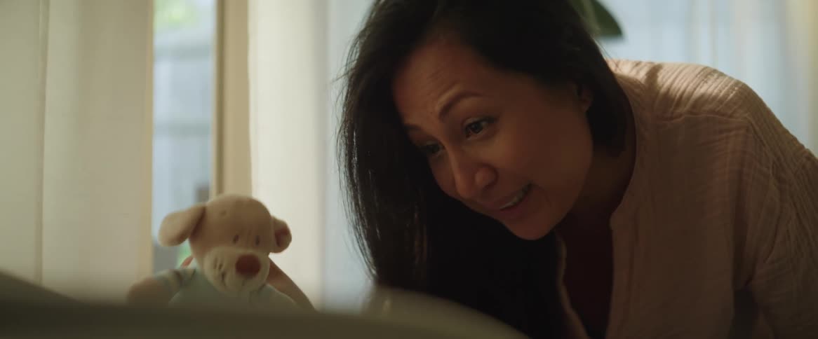 Mother uses a plush toy to play with her baby at home