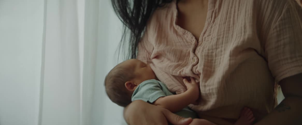 A woman smiles at her baby while breastfeeding