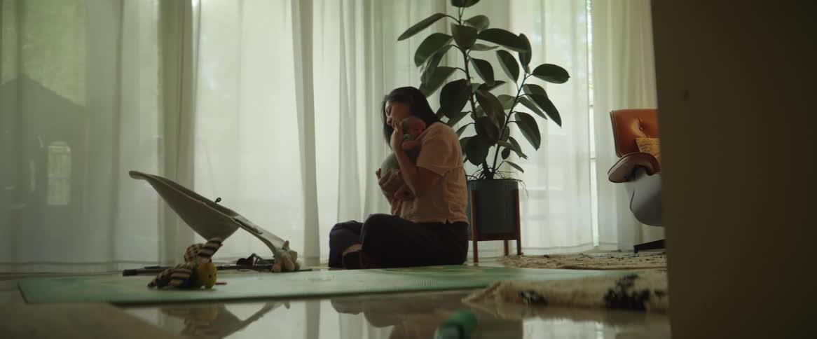 A young woman leans over and picks up a very tiny infant