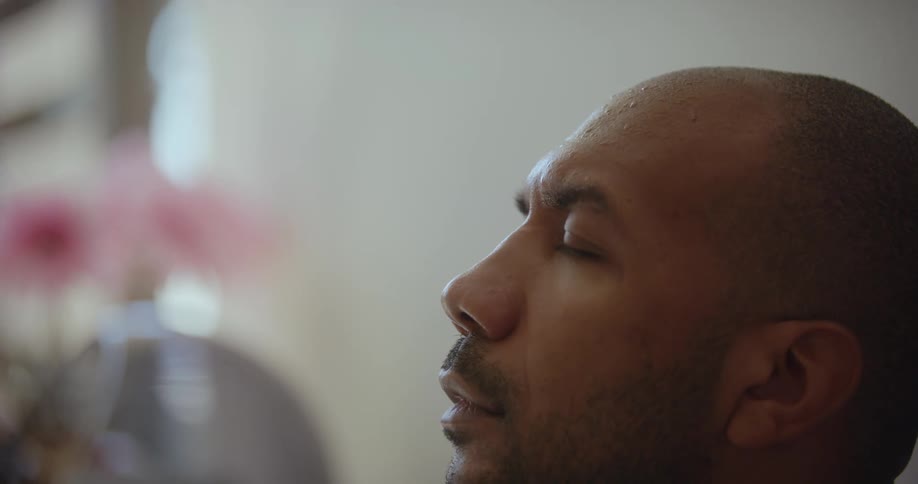 A person holds a thermometer to a mans head who seems sick