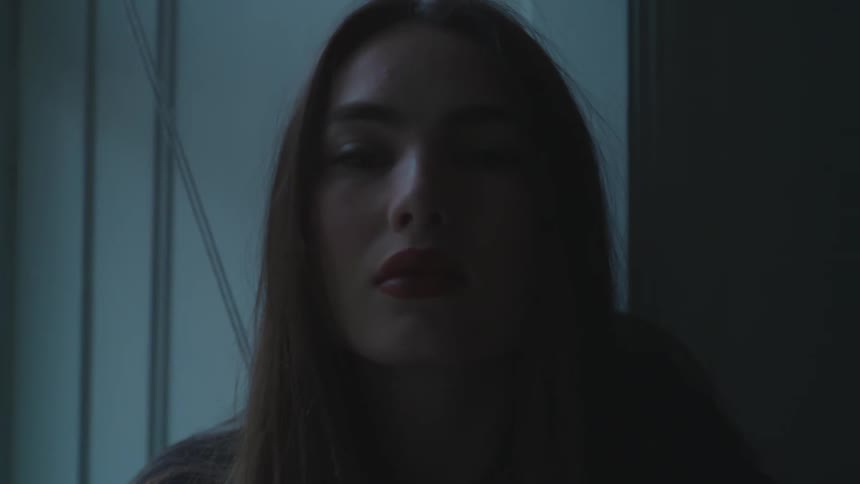 Face of a pale woman with long hair turning to show her profile