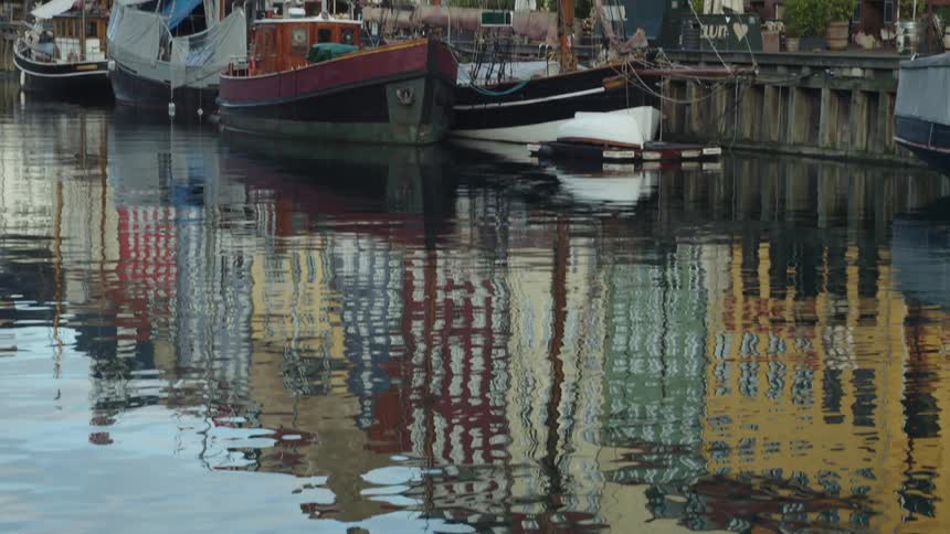 River water reflects boats and nearby apartment buildings