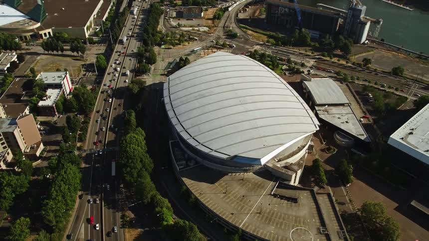 Aerial footage with a tilt up from Moda Center showcasing downtown Portland Oregon revealing the Willamette River high rise buildings and the city bridge