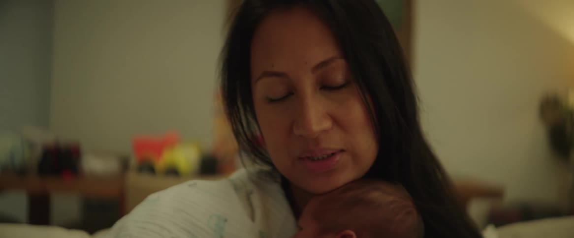 A woman cradles a small infant against her chest while patting its back