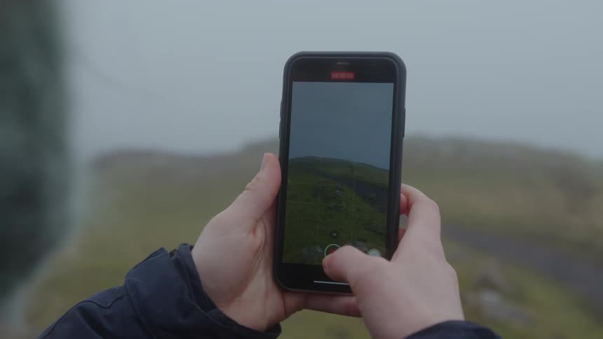 Person photographing the cloudy landscape with a smartphone