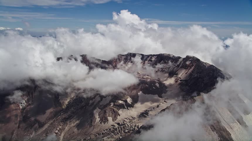 Aerial view of Mount St Helens with cloud coverage showcasing the rocky terrain of the mountain range in Washington