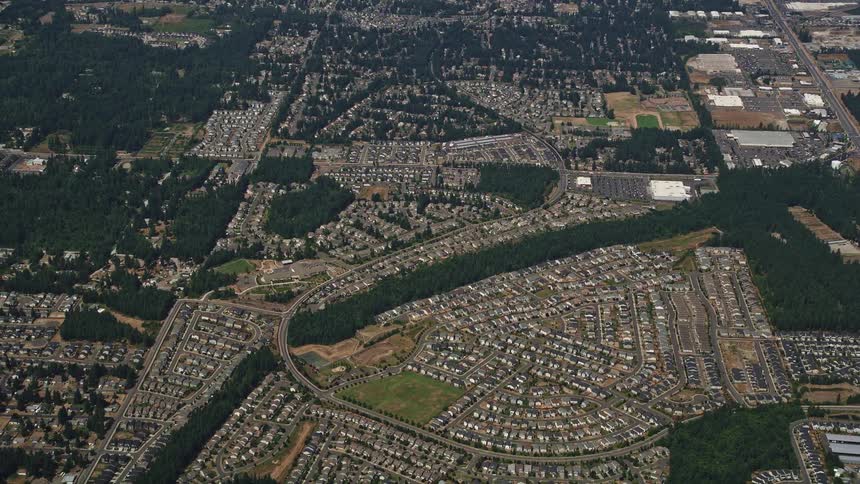 Aerial view of Renton Washington suburban neighborhoods with closely built houses and small plots of trees throughout bathed in sunshine