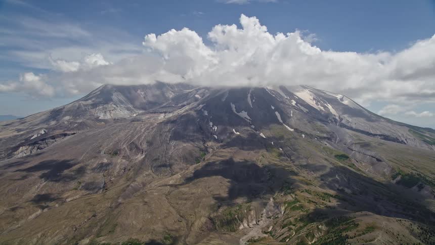Approaching cloud-capped Mount St Helens with patches of snow on a partly cloudy day in Washington showcasing the natural beauty of the mountain landscape in the Pacific Northwest