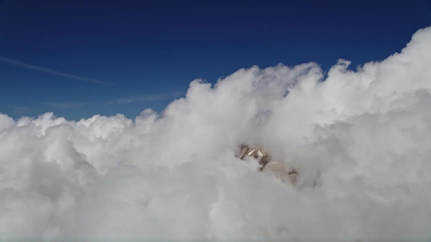 Aerial footage captures the majestic white clouds blanketing Mount St Helens showcasing its snowy slopes in Washington