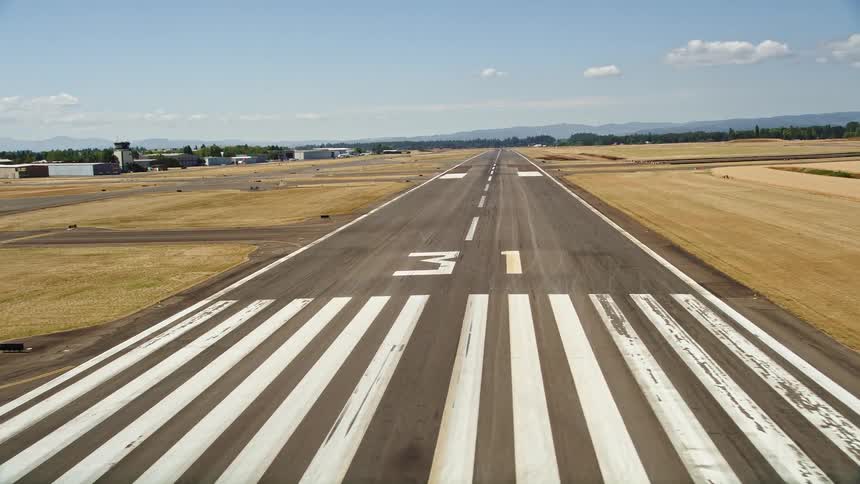 Low flying aerial view of an airplane approaching the runway at Hillsboro Airport in Oregon with beautiful sunshine and scenic landscape