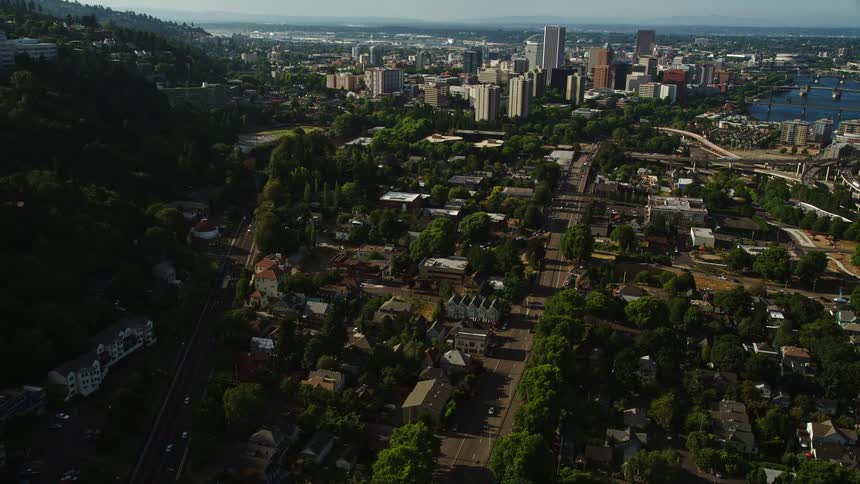 Tracking a gondola over homes and city streets in Southwest Portland Oregon showcasing the vibrant and sunny suburban neighborhood with stunning aerial views of the city's streets and transportation