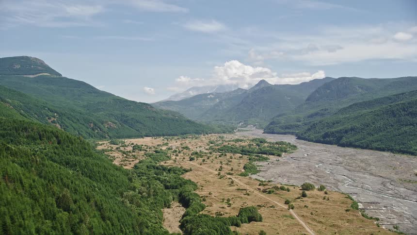 Aerial footage showcasing a wooded slope the North Fork Toutle River and Mount St Helens in Washington with a focus on the natural landscape and the river's journey through the mountains