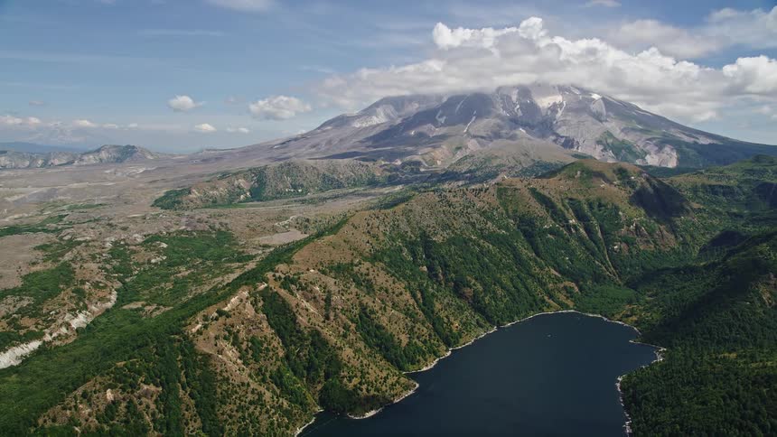 Aerial footage flies over Castle Lake towards Mount St Helens showcasing the beautiful landscape of mountains and water bodies in Washington