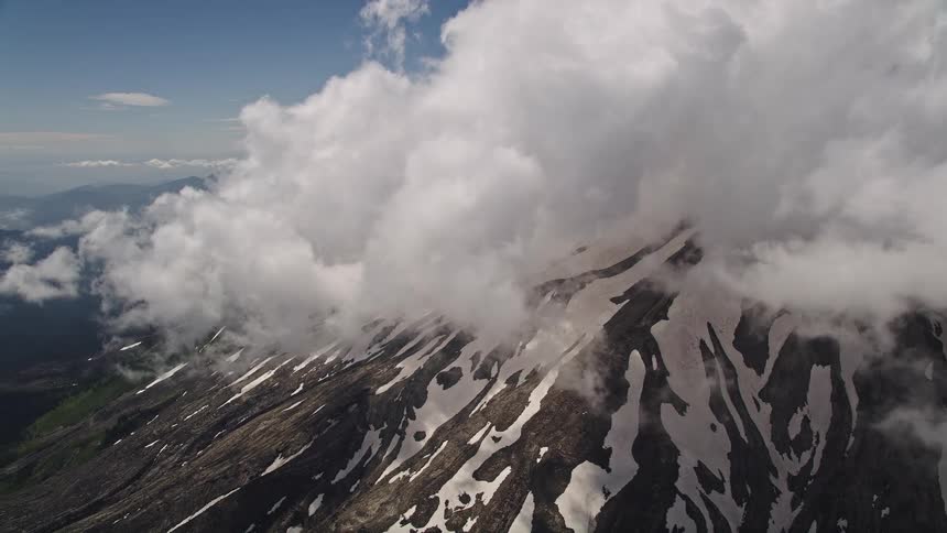 Aerial footage of snowy Mount St Helens with summit clouds in Washington