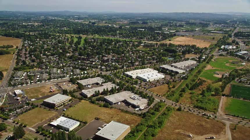 Aerial footage of a sunny suburban neighborhood with office buildings across the street in Hillsboro Oregon