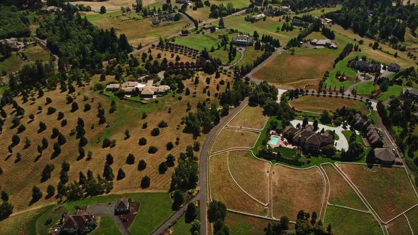 Aerial footage approaching an upscale country home surrounded by lush vegetation in Ridgefield Washington during daytime