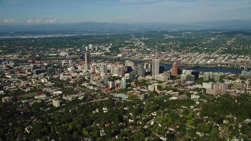 Aerial view of Downtown Portland Oregon with tall buildings and a river on a sunny day