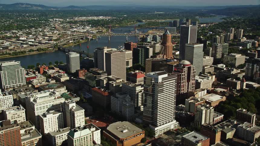 aerial footage flying over city buildings towards skyscrapers in Downtown Portland Oregon on a sunny day approaching the Willamette River