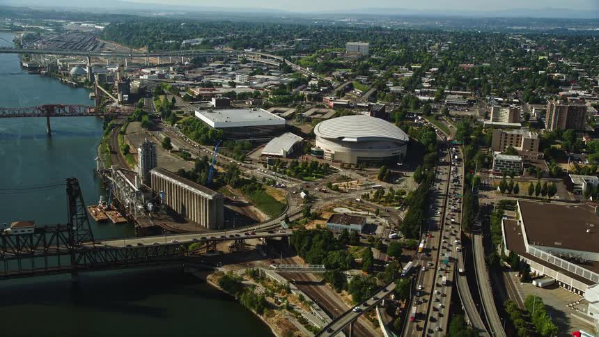 Approaching the Moda Center from the Willamette River in Northeast Portland Oregon capturing the vibrant cityscape and the iconic steel bridge in the footage