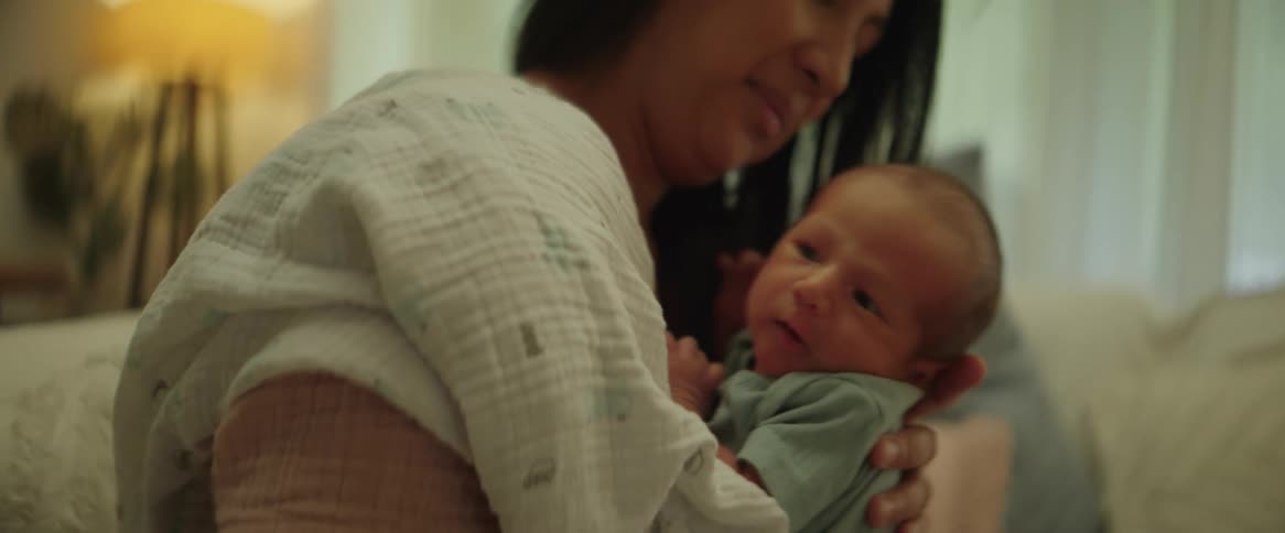 A close up of a mother holding her newborn baby patting him on the back as she sways side to side