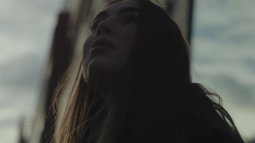 A young woman looking up and to the side worriedly