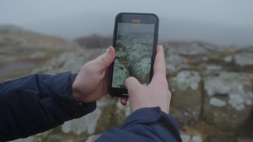 Person recording video of landscape with mobile phone