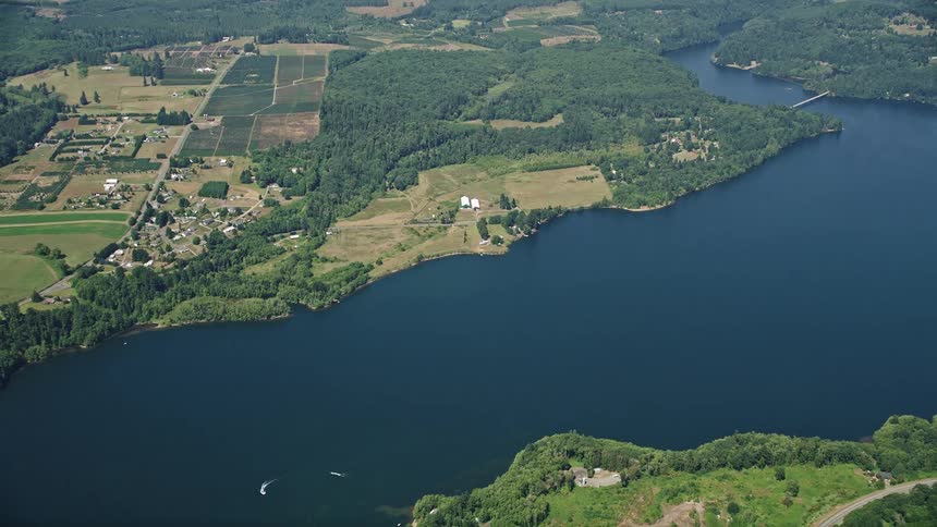 Aerial view of farms fields and Mayfield Lake in Silver Creek Washington as the camera flies away in the day time