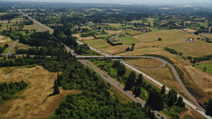 Aerial view of I-5 with light traffic passing by farm fields in Ridgefield Washington during a sunny day