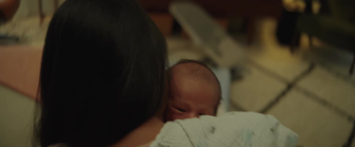 Mother holds very young baby against their cloth covered shoulder