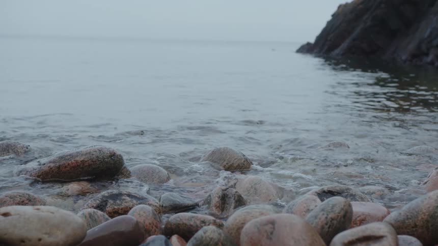 Closeup of the shore of the beach with stones in a round shape