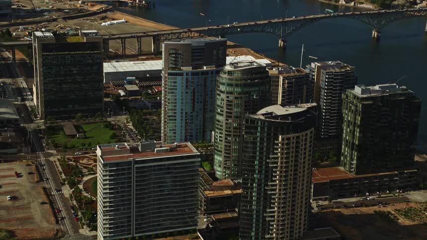 Aerial footage of condominium high-rises in South Waterfront Portland Oregon with skyscrapers beside a river in a city during the day