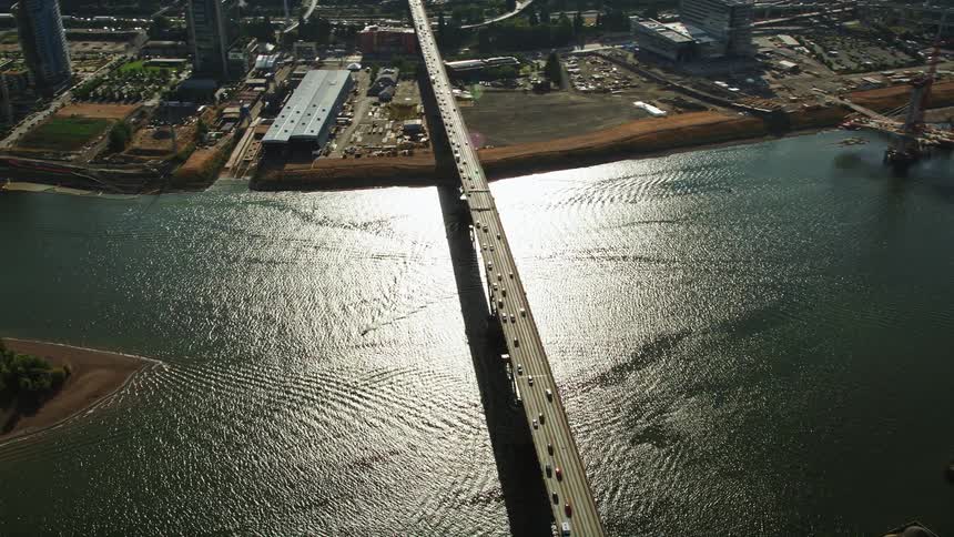 A stunning aerial view of Downtown Portland Oregon featuring the Ross Island Bridge and the cityscape as the drone orbits and reveals the metropolis by the river with traffic-filled bridges and high-rise buildings