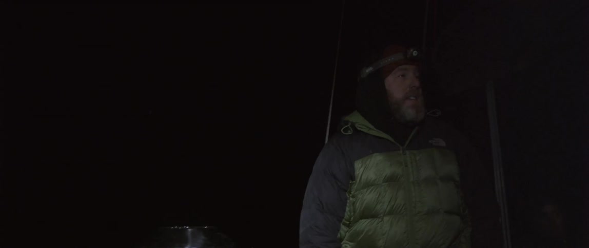 A man is talking as he stands on a boat at night