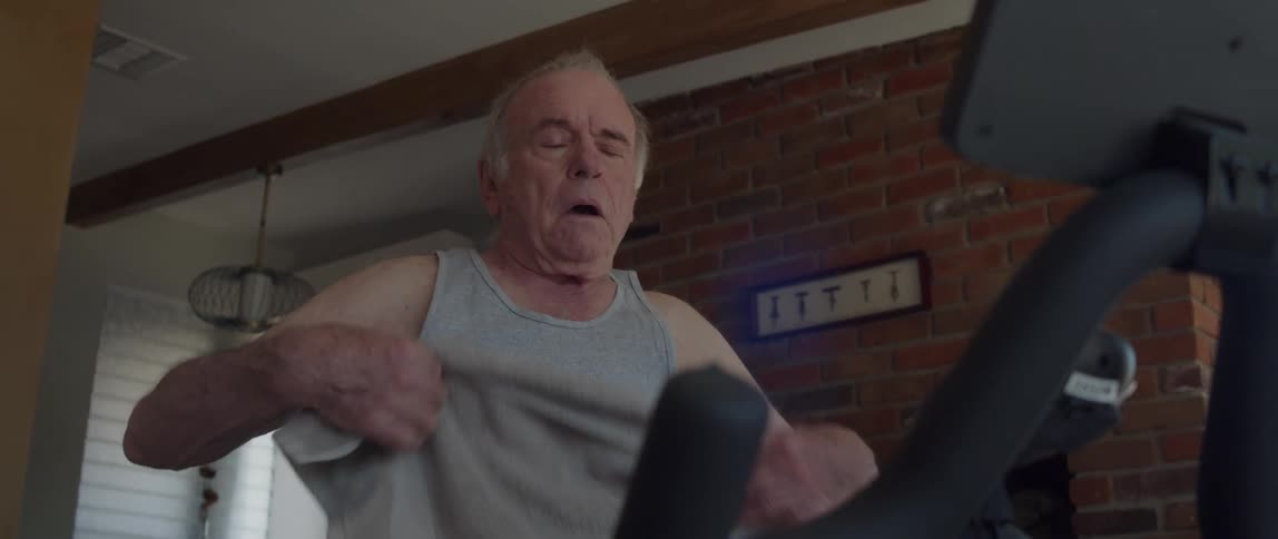 An elderly man wipes sweat from his face after exercising