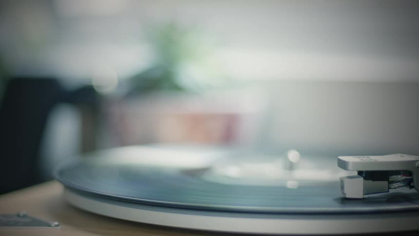 Vinyl record turns slowly on a turntable with a blurry background