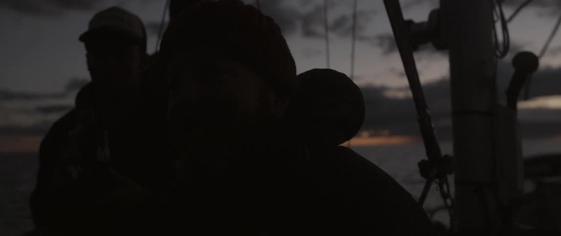 A group of people ride on a boat at dusk