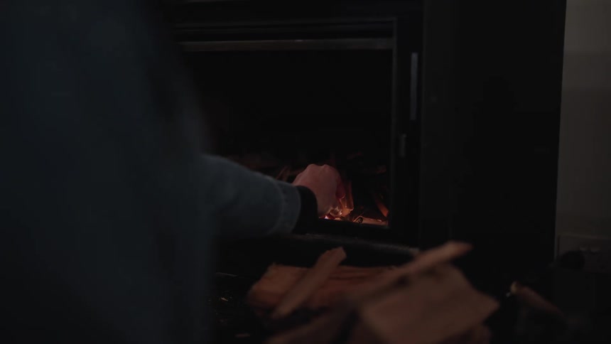Two human hands lighting a fireplace with a match with fire