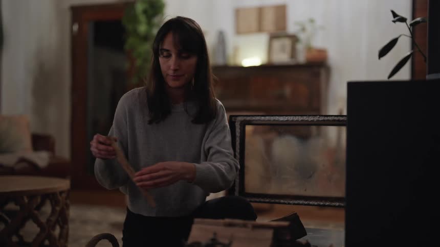 A woman puts wood inside a fireplace