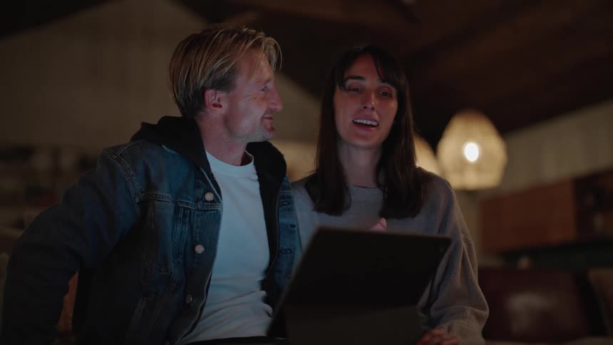 A man and woman talk while looking at a tablet