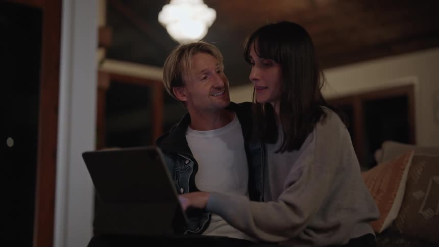 A couple look at a tablet and kiss