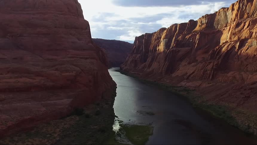 A stream runs through two tall cliffs on a cloudy day