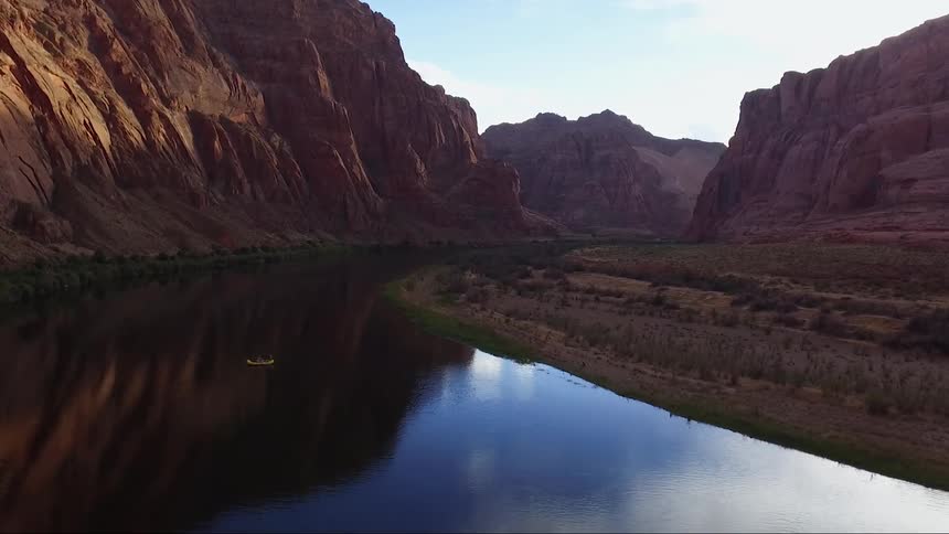 A yellow raft floating on a river in a valley