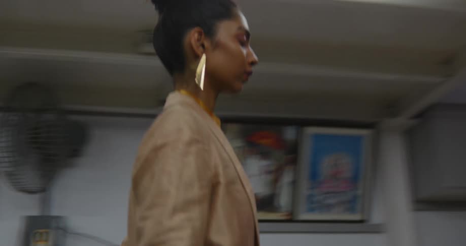 Model wearing fashionable outfit walks through mostly empty sewing workshop