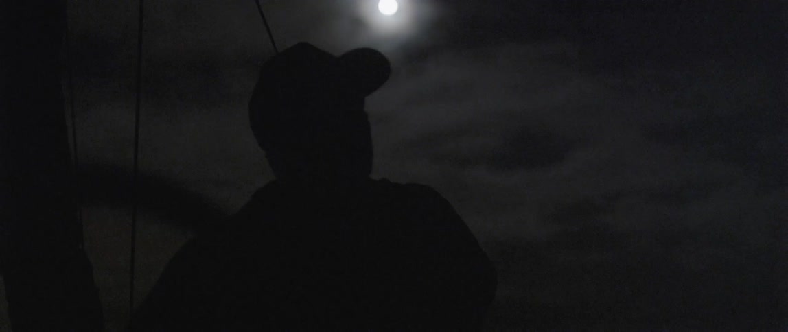A person is standing at night under a full moon