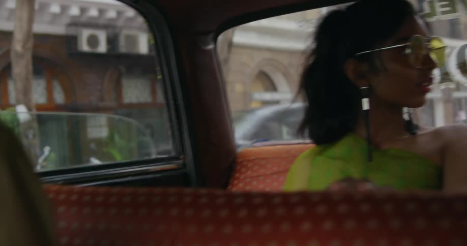 A woman moves across the back seat of a taxi so she can look out the window