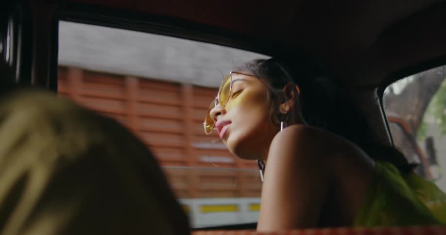 Woman with sunglasses and earrings sticks her head out of the car window