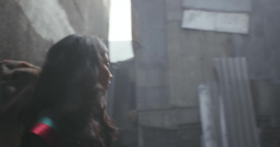 A woman with long dark hair walks through a building and looks around