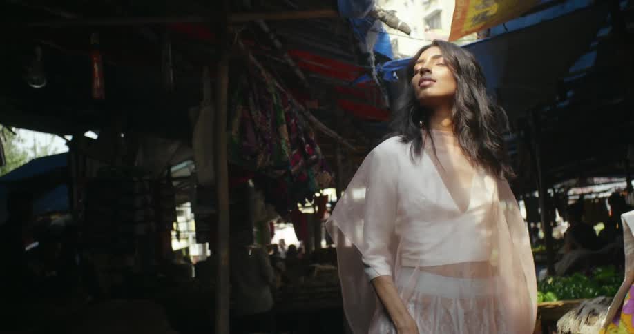 Woman wearing fashionable outfit walks through bazaar near apartment building