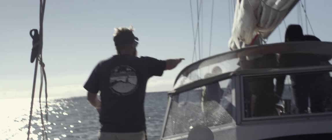 A man is walking toward the mast of a sailboat